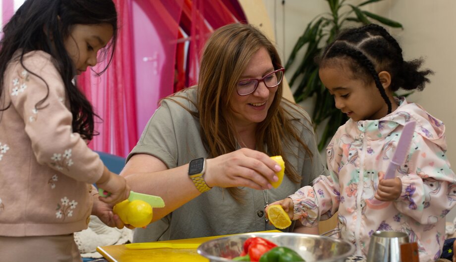 Teacher playing with real fruit and vegetables with two children