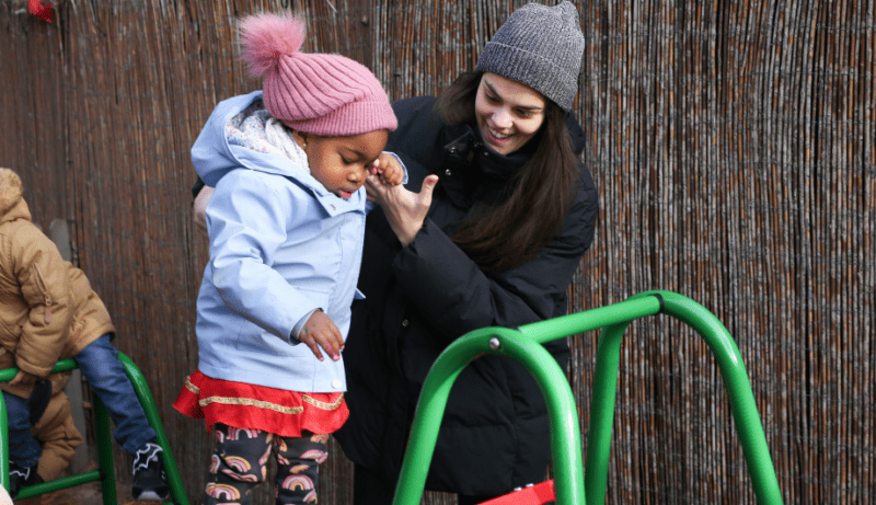 Staff member helping a child on a climbing frame