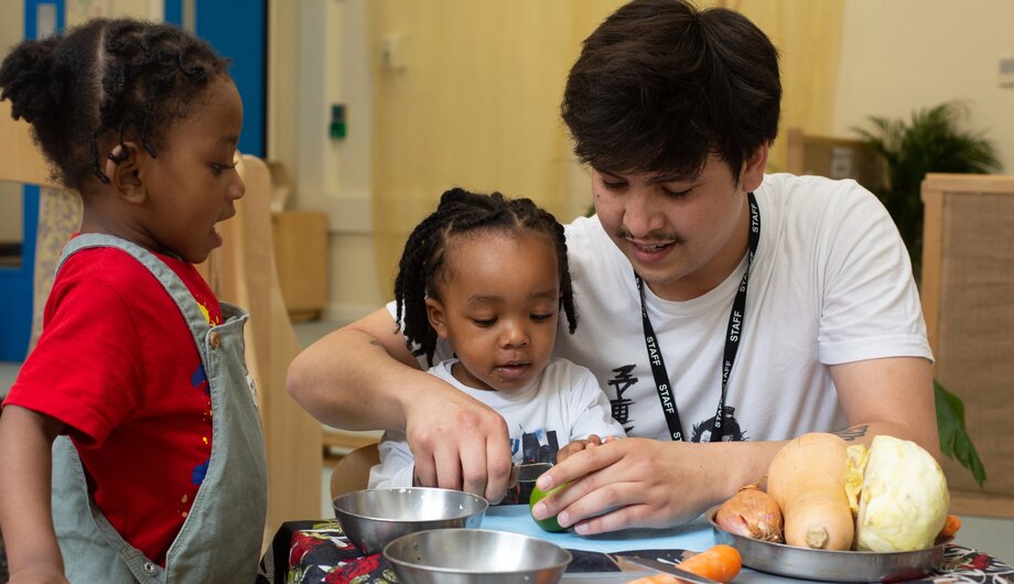 staff helping children learn how to cut vegetables