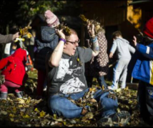 Group of children and a teacher playing with fallen leaves