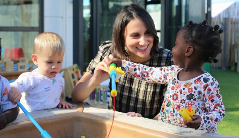 staff and children playing with water outside