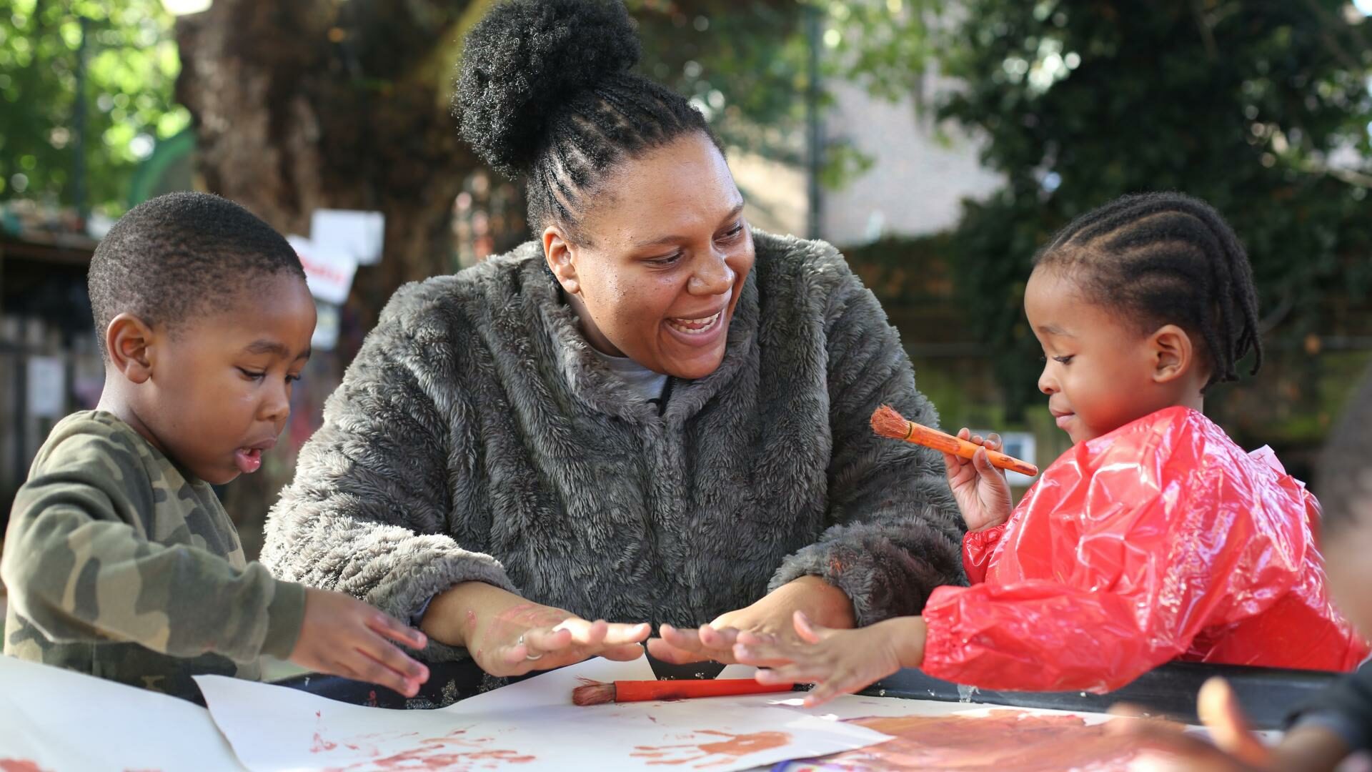 Teacher and children enjoying painting outdoors