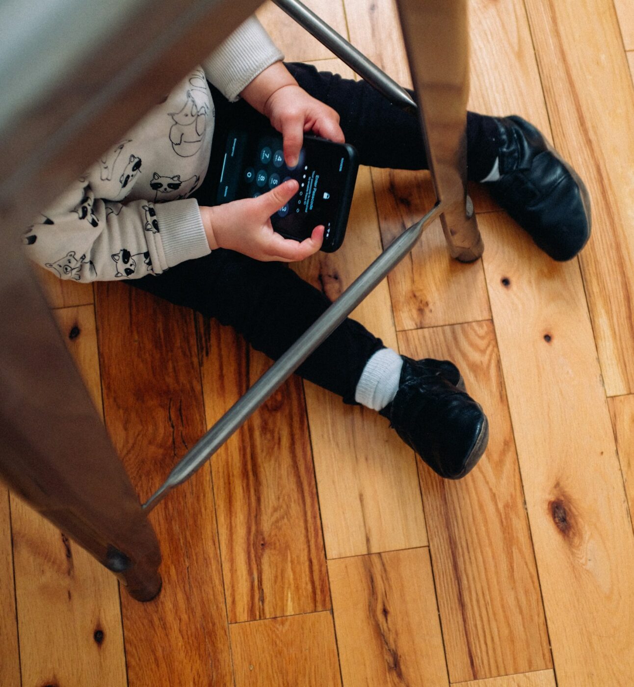 Child using mobile phone under a chair