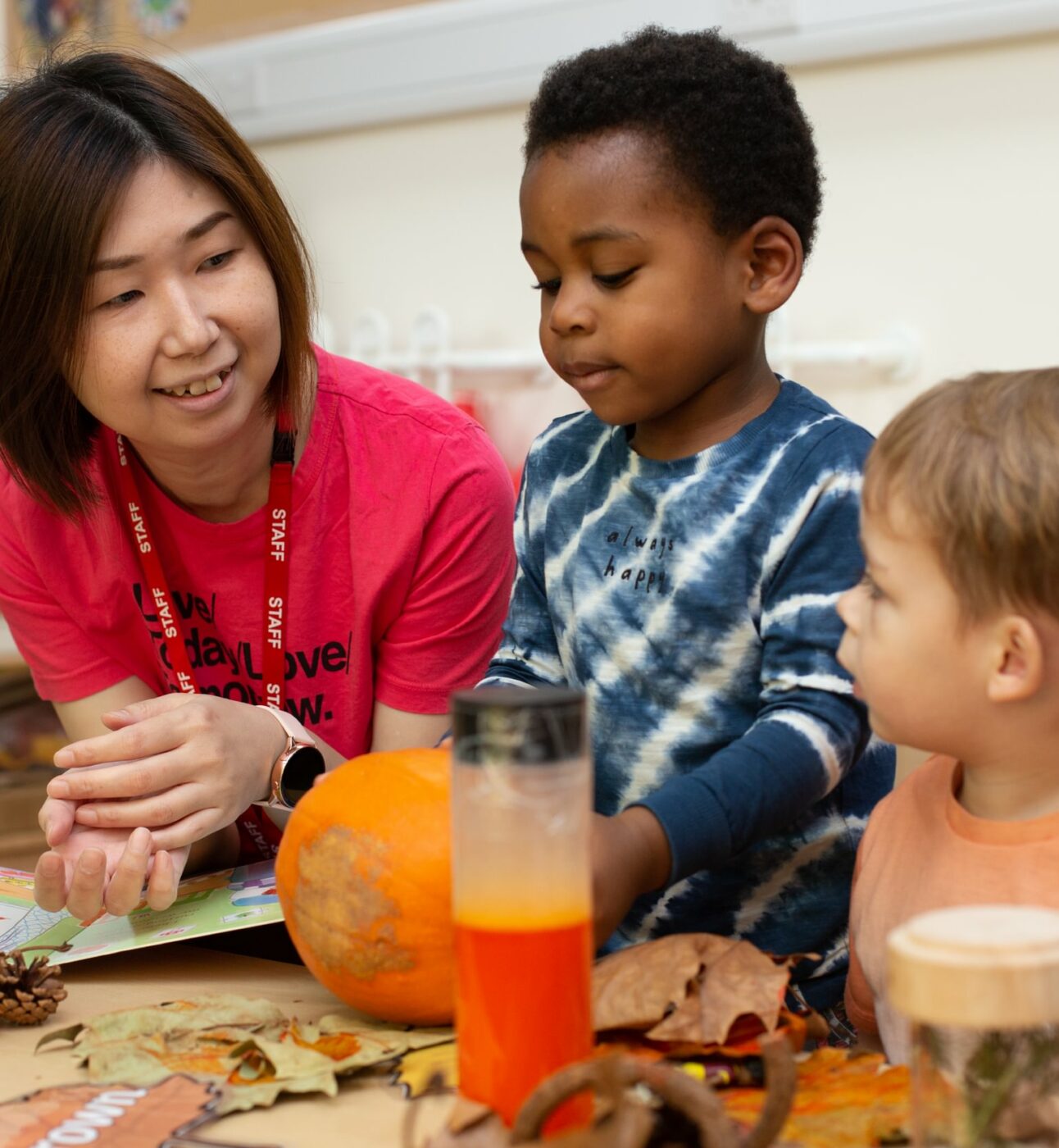 Staff member talking to two children looking at a pumpkin