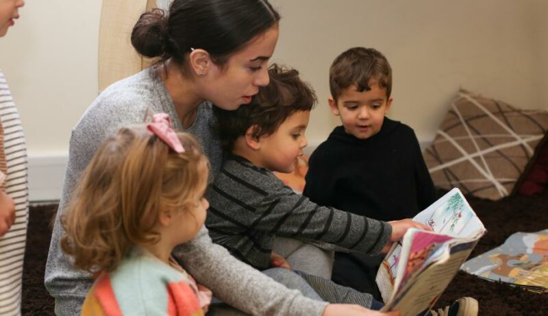 Staff member reading a book to a group of children