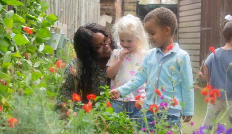 Staff member showing children flowers in Bessborough garden