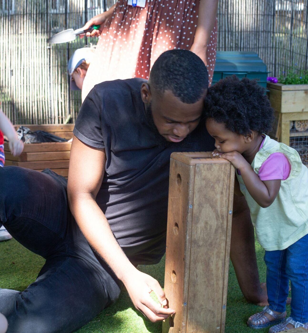 Staff and child looking into a wooden block