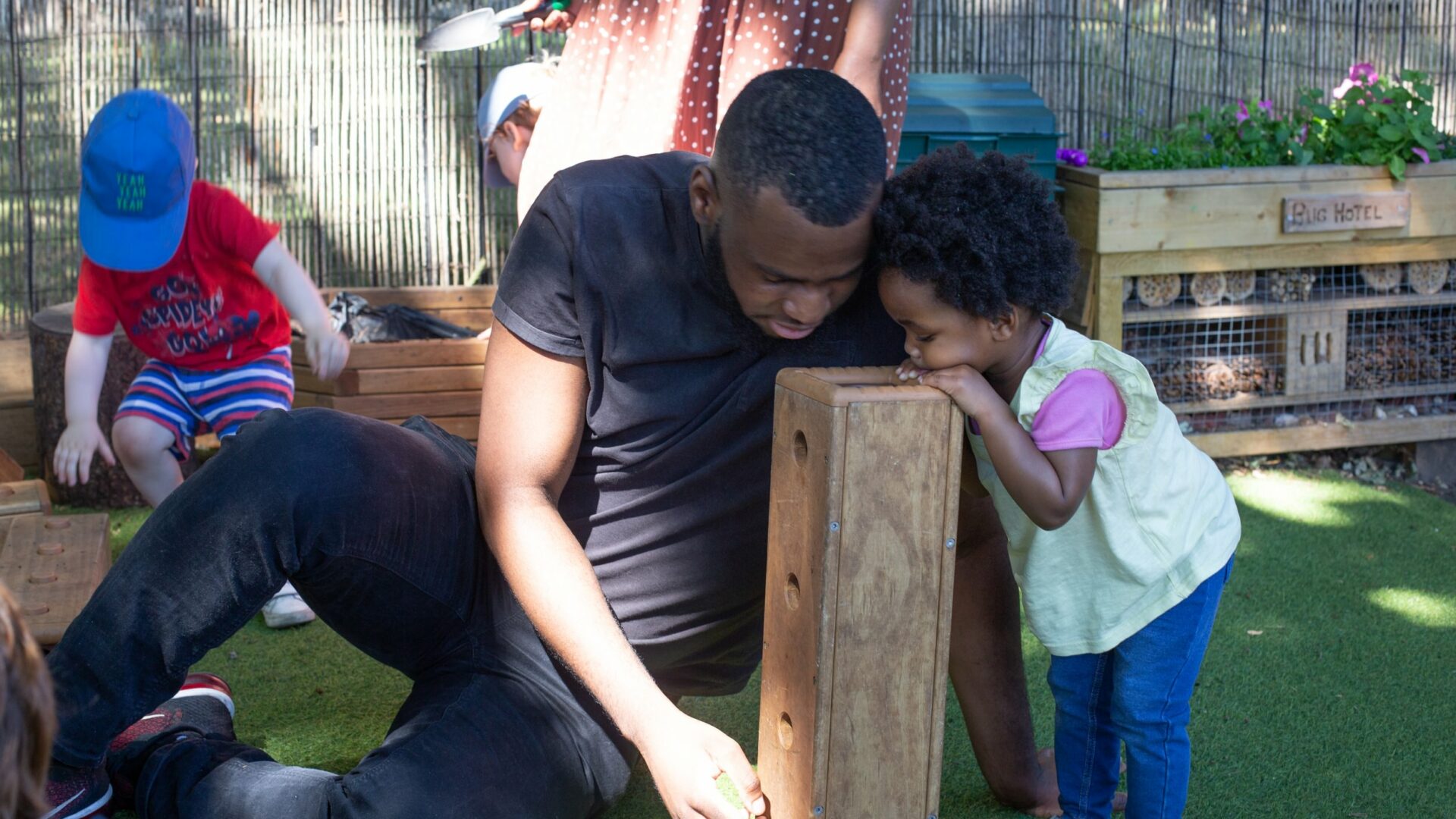 Staff and child looking into a wooden block