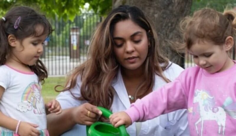 Teacher helping two children with a watering can