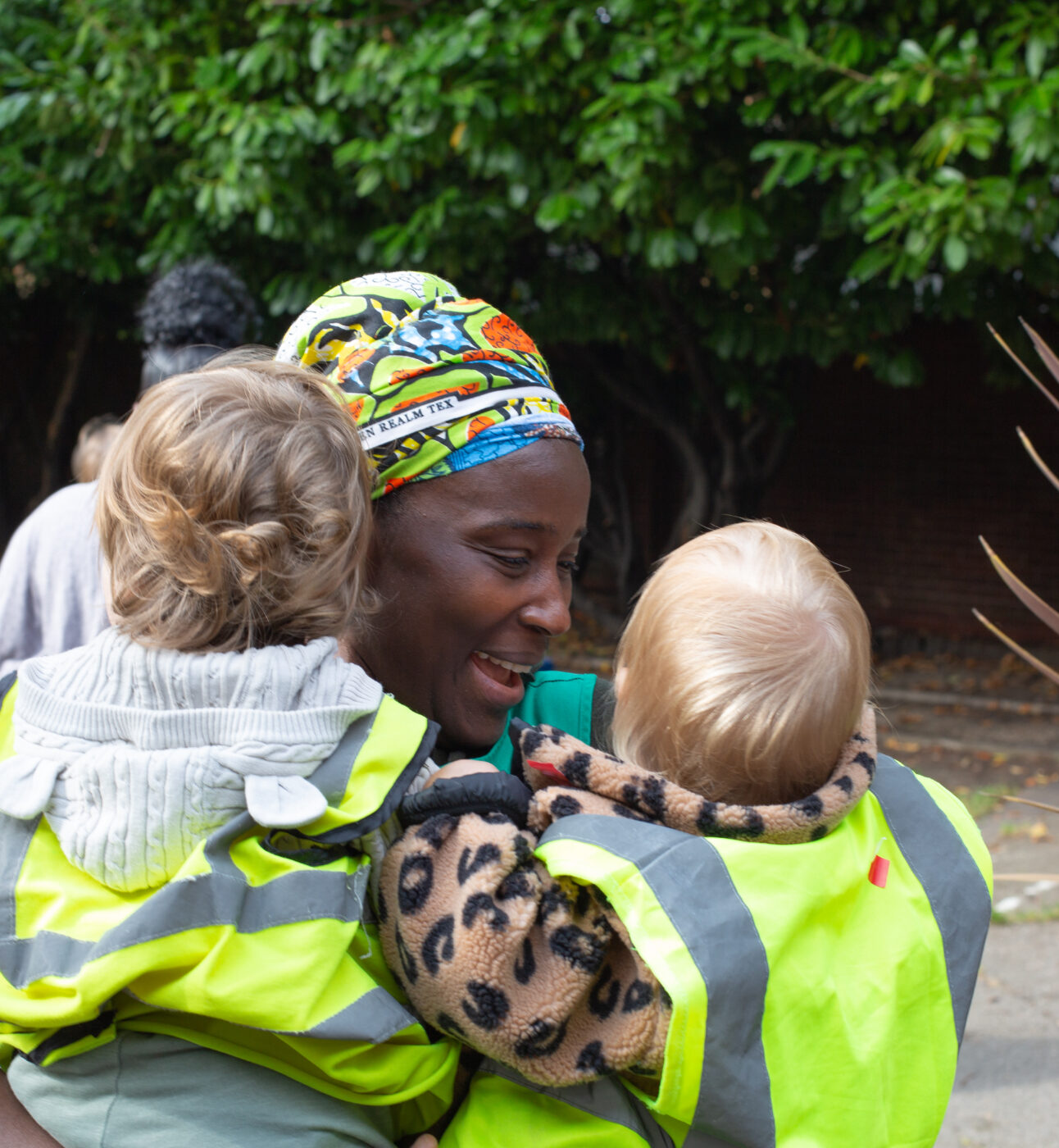 A staff member giving two children a hug