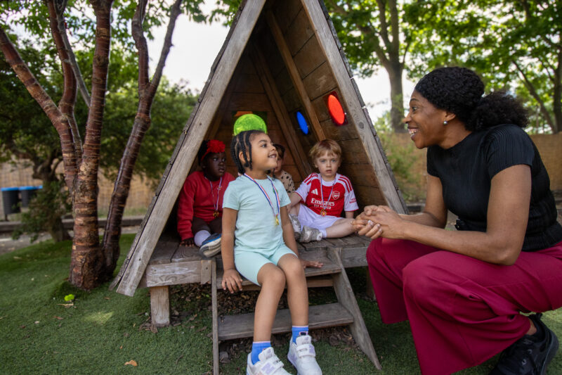 Gumboots East Dulwich Nursery teacher and children talking outside.